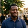 Kelechi smiling outdoors on an Abuja street at golden hour
