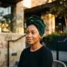 Zainab in a green headwrap, seated outdoors at golden hour in Ibadan